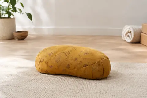 Coussin de méditation demi-lune en coton jaune indien posé sur un tapis dans un studio lumineux