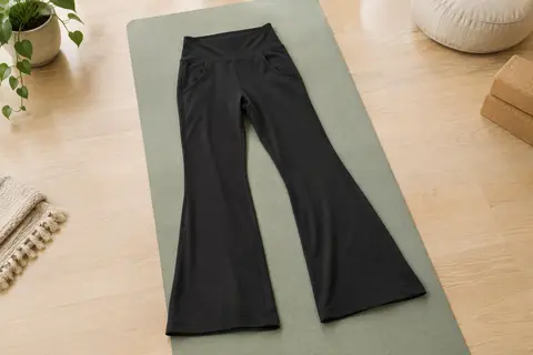 Legging de yoga noir à taille haute, coupe évasée et deux poches avant, disposé dans un studio lumineux.