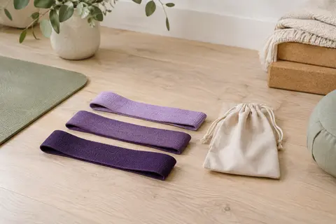 Trois bandes élastiques tressées lavande et violettes disposées avec leur sac de rangement