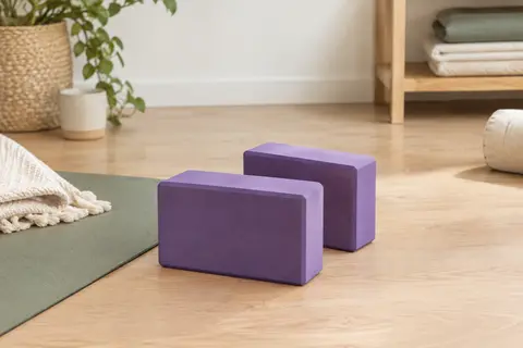 Deux briques de yoga en mousse EVA pourpre posées sur un sol en bois clair dans un studio lumineux.