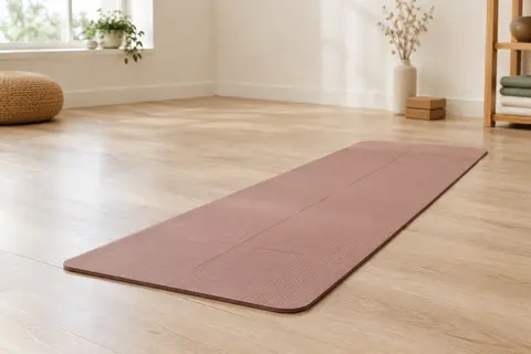 Tapis de yoga nude vieux rose en TPE avec texture et repères d’alignement, posé sur un sol en bois clair.